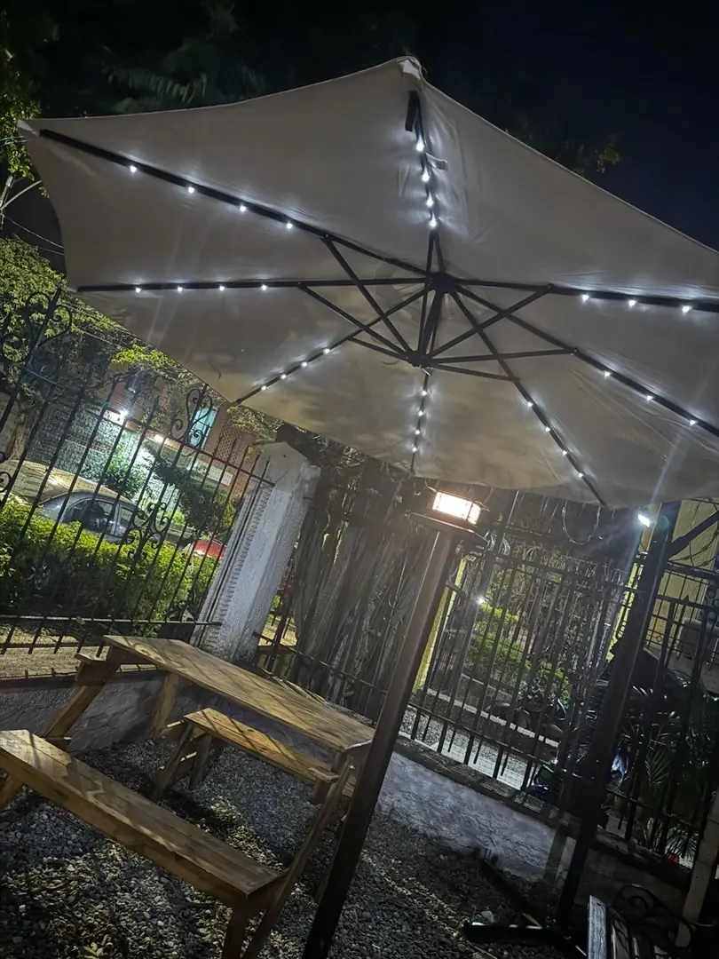 Terraza de Le Mani in Pasta de noche, con mesa de madera y sombrilla con luces