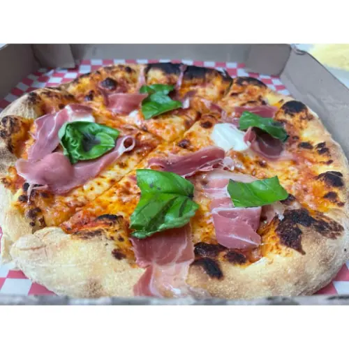 Pizza con prosciutto, mozzarella y albahaca fresca